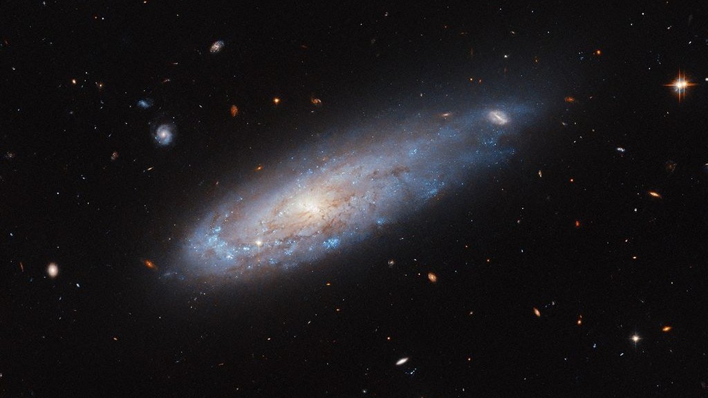 Distorted galaxy whizzes through crowded cluster in new Hubble Telescope image