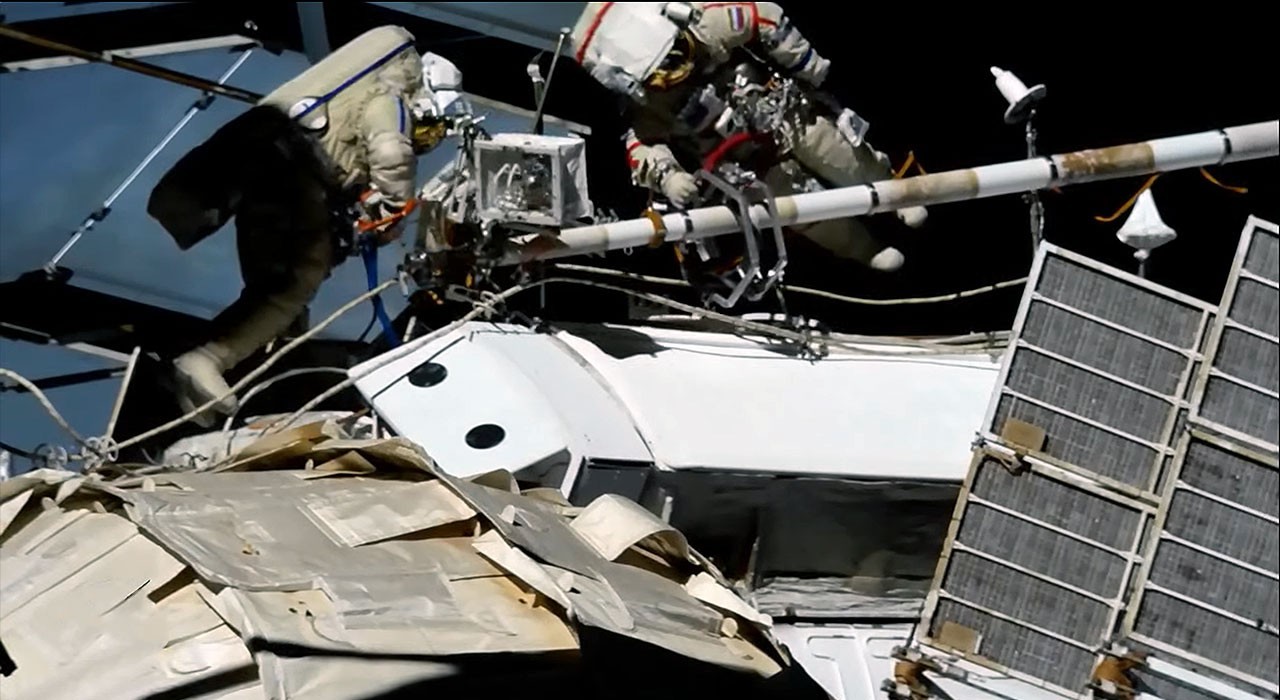 Cosmonauts on spacewalk run power and data to new space station module